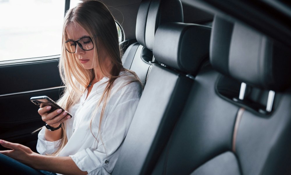 woman passenger using phone in back seat of car